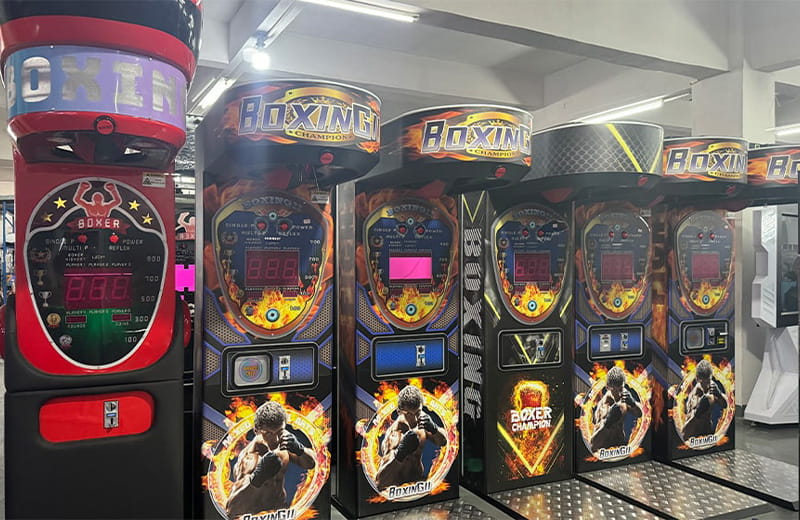 Multiple red and black boxing arcade machines with digital score displays for strength testing and competitive fun.