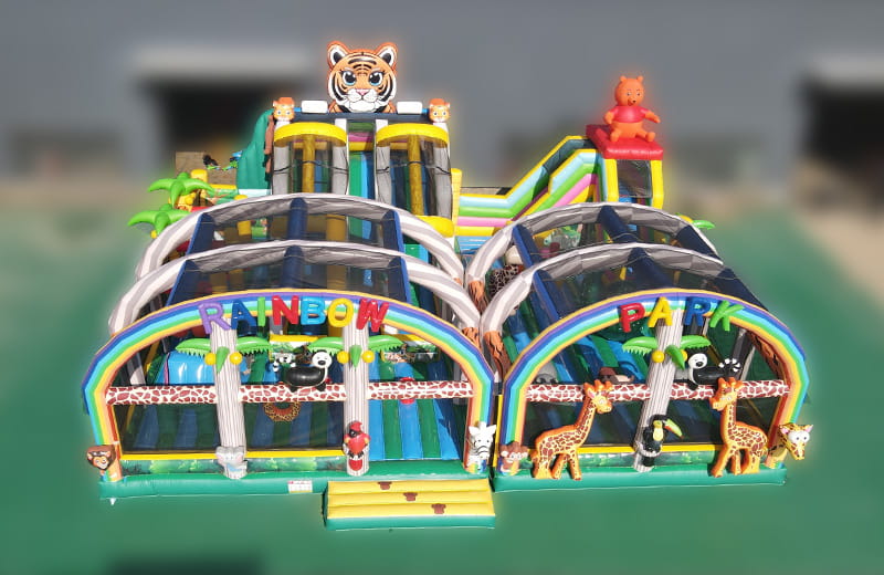 Comprehensive jungle themed inflatable playground with animal graphics, rainbow arches, and protective netting for children's safety.