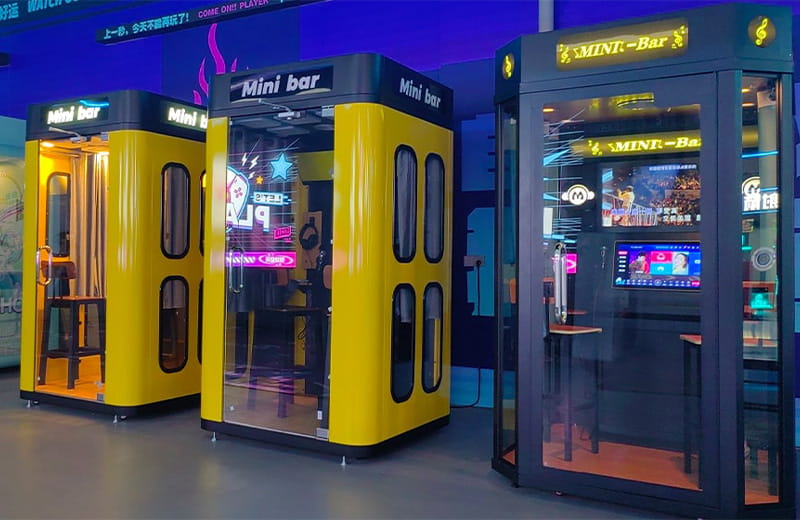 Compact yellow and black mini KTV booths with soundproof glass, touchscreens, and high-quality microphones for private singing.
